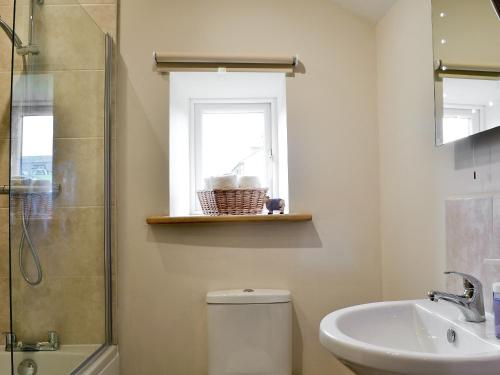 a bathroom with a toilet and a sink and a window at Little Grans Cottage in Cowling