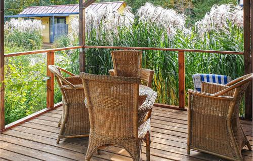 four wicker chairs sitting on a wooden deck at Lovely Home In Biskupiec With Lake View in Biskupiec