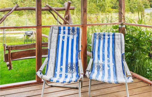 two chairs sitting on top of a deck at Lovely Home In Biskupiec With Lake View in Biskupiec