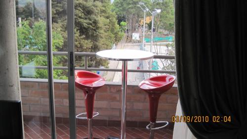 a table and two red stools in front of a window at International House Co-Living in Medellín