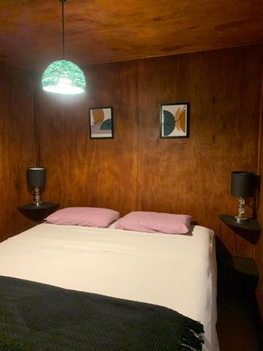 1 dormitorio con 1 cama grande y 2 lámparas en Cabaña en entorno natural, en Punta Ballena