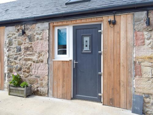 a garage with a blue door and a stone wall at Uk7384 - The Hayloft in Newmilns