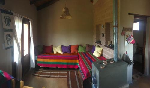 ein Wohnzimmer mit einer Couch mit einer bunten Decke in der Unterkunft Ranchos en Payogasta - Cachi in Payogasta