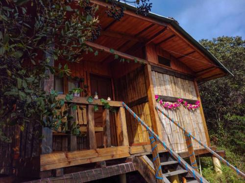 a wooden house with a porch and pink flowers at Entre Rocas y Cristales in Ráquira