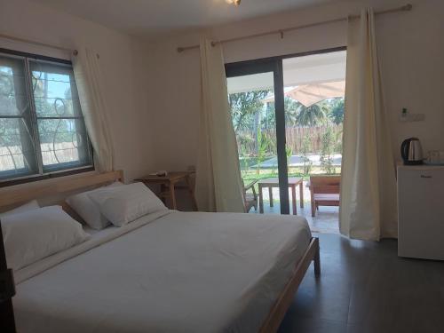 1 dormitorio con cama blanca y ventana grande en Nice Home Stay @Samroiyot, en Sam Roi Yot