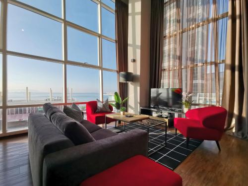 sala de estar con muebles de color rojo y ventanas grandes. en Maritime Suites Holiday Rental, en George Town