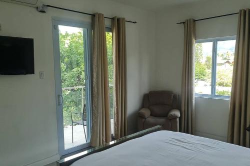 a bedroom with a bed and a chair and a window at Harloes Luxury Suite - Kingston Jamaica in Kingston