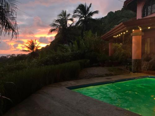 a swimming pool in front of a house with a sunset at Casa Papaya in Uvita