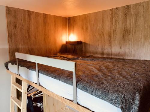 un lit dans une chambre avec un mur en bois dans l'établissement Maisonnette 5 personnes avec piscine et parking - FR-1-476-170, à La Faute-sur-Mer