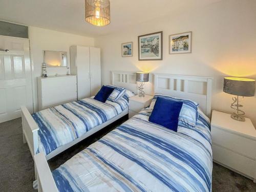 two beds in a bedroom with blue and white sheets at Seapoint House in Cleveleys