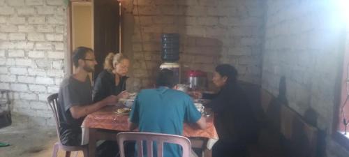 a group of people sitting at a table eating food at Karleta Homestay in Ruteng