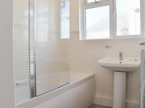 een witte badkamer met een wastafel, een bad en een douche bij Seascape in Sidmouth