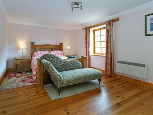 a bedroom with a chair and a bed and a window at The Barn - S4593 in Lochearnhead