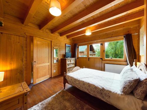 a bedroom in a log cabin with a bed and a window at Alpine Lodge in Pentney