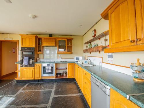 a large kitchen with wooden cabinets and appliances at Fishermans Cove - W42425 in Pierowall
