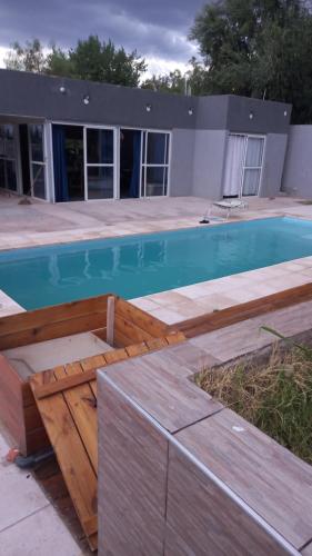 una piscina con un banco de madera junto a un edificio en MAIPU Apart en Maipú