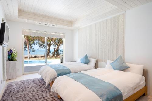 Dos camas en un dormitorio con vista al mar. en Ocean Front Villa Ishigakijima Ⅲ, en Ishigaki Island