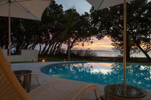 a swimming pool with two chairs and an umbrella at Ocean Front Villa Ishigakijima Ⅲ in Ishigaki Island