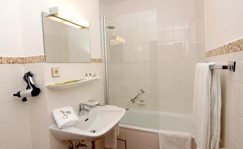 y baño blanco con lavabo y ducha. en Garni Hotel Leitl GmbH, en Eggenfelden