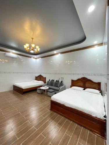 a bedroom with two beds and a couch at Nhà nghỉ Quỳnh Như in Cao Lãnh