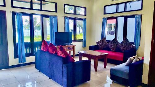 a living room with two blue chairs and a tv at Aman Gati Hotel Lakey in Huu