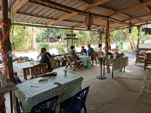 um grupo de pessoas sentadas em mesas em um pátio em Good Time Resort Koh Kood em Ban Lak Uan