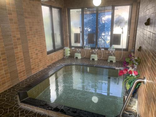 a swimming pool in a bathroom with windows at Hotel Suehiro in Matsumoto