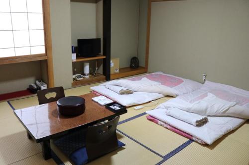 a room with two beds and a wooden table at Hotel Suehiro in Matsumoto