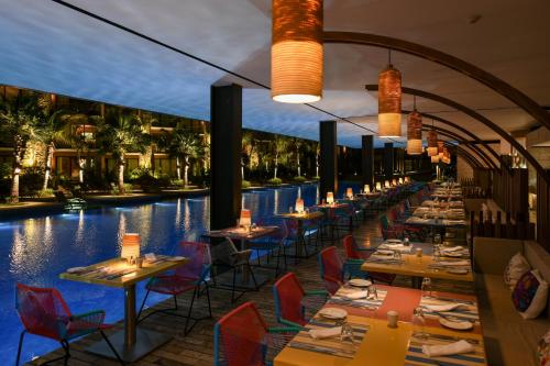 a restaurant with a pool with tables and chairs at Hotel Xcaret Mexico All Parks All Fun Inclusive in Playa del Carmen
