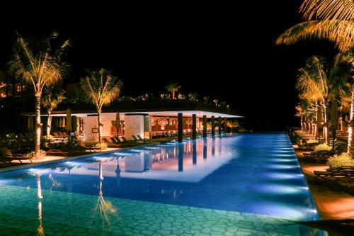 a swimming pool at night with palm trees and a building at Hotel Xcaret Mexico All Parks All Fun Inclusive in Playa del Carmen