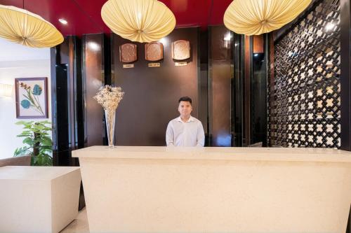 a man standing behind a counter in a restaurant at Hanoi Center Silk Charming Hotel & Travel in Hanoi