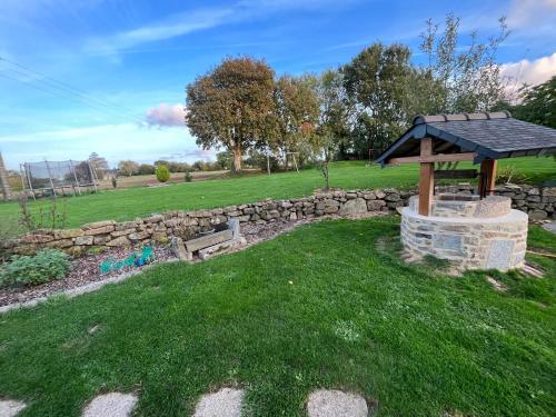 a garden with a stone wall and a gazebo at Jolie chambre dans une dépendance de longère bretonne in Plouvara
