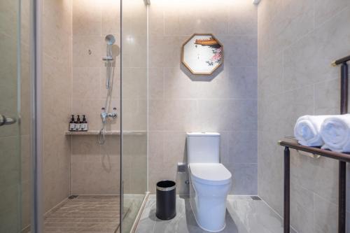 a bathroom with a toilet and a glass shower at Rezen Longuu Hotel - Universiade Center Longgang Shenzhen in Longgang