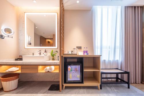 een badkamer met een wastafel en een spiegel bij Rezen Longuu Hotel - Universiade Center Longgang Shenzhen in Longgang