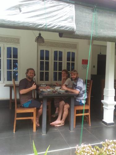 three people sitting at a table under an umbrella at Eagle Wings Holiday in Belihul Oya