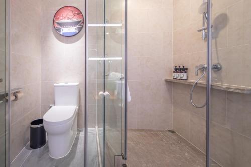 a bathroom with a toilet and a glass shower at Rezen Longuu Hotel - Universiade Center Longgang Shenzhen in Longgang