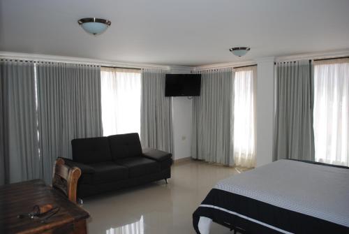 a bedroom with a bed and a chair and a television at COLOMBIA-Hotel Hontibon in Pamplona