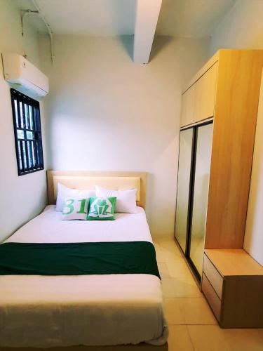 a bedroom with a large white bed with green pillows at Homestay 81 Batu Batam in Nagoya