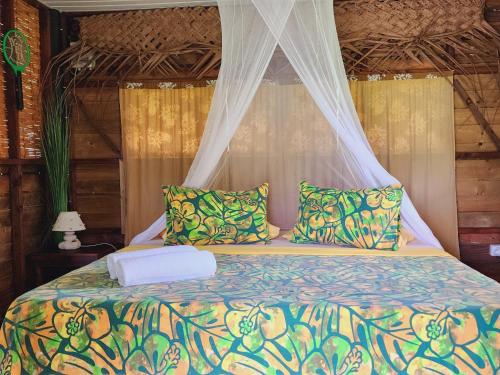 a bedroom with a bed with a canopy and pillows at Moanaiti Lodge in Maheva
