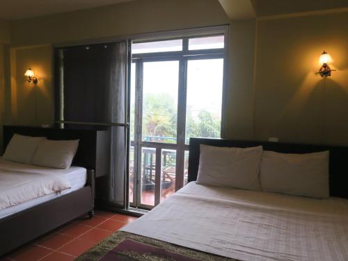 a bedroom with two beds and a large window at River Dolphin Hotel in Kratie