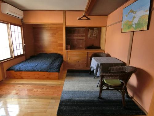 Shirokuma Inn في توياما: غرفة نوم بسرير وطاولة وكراسي