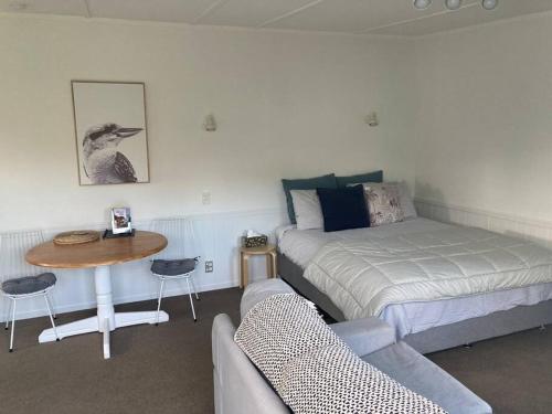 1 dormitorio con cama, mesa y sofá en Cosy Studio on Hyde, en Taupo