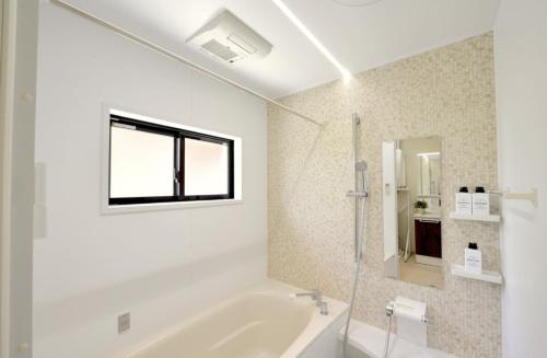 a white bathroom with a tub and a window at Orange Line in Inbu