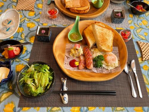 a table with a plate of food with bread and vegetables at Dining & Stay 38 Miyahira in Zamami