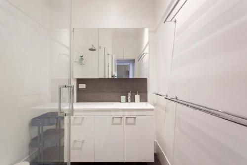 ein weißes Badezimmer mit Waschbecken und Spiegel in der Unterkunft Home Away - 2 Bedroom Cottage in Bicton