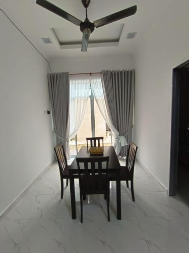 a dining room with a table and chairs and a ceiling fan at JRK HOMESTAY A in Jertih