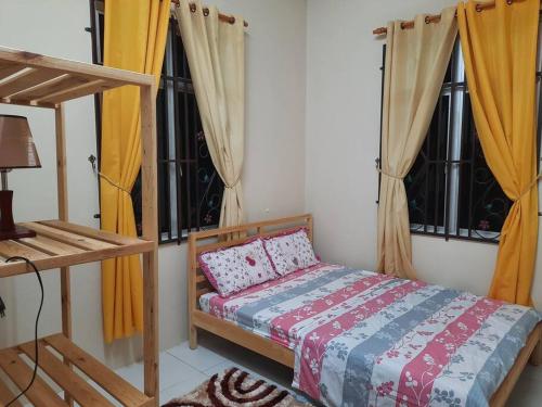 a bedroom with a bed and two windows at T'Rai Homestay in Dungun