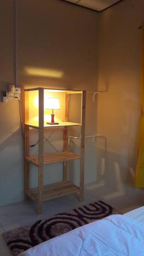 a room with a bed and a table with a lamp at T'Rai Homestay in Dungun