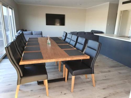 Olley's Place في Wellington East: قاعة اجتماعات مع طاولة خشبية وكراسي سوداء