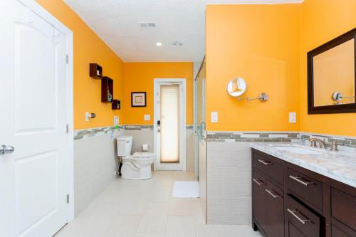 a bathroom with orange walls and a toilet and a sink at Charming 3Bd w/ Pool Close to Disney @ 7826 Indian Ridge in Orlando